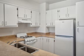 a kitchen with white cabinets and white appliances and a counter top