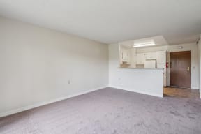 an empty living room with white walls and a kitchen