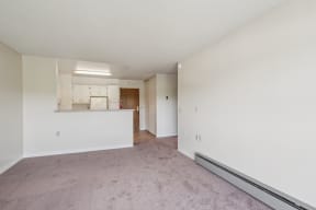 an empty living room and kitchen with white walls and carpet