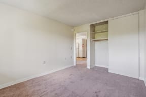 the living room of an apartment with carpet and white walls