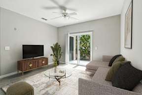 A living room with a grey couch, a coffee table, and a flat screen TV.