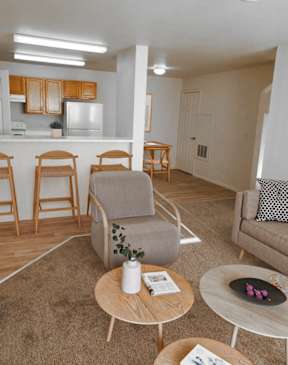 A living room with a grey sofa, a wooden coffee table, and a kitchen area in the background.