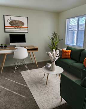 A room with a green couch, a white chair, a desk with a computer, and a painting on the wall.