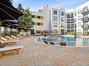 A large outdoor swimming pool surrounded by sun loungers and umbrellas.