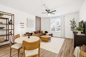 A living room with a white ceiling fan and a brown rug.