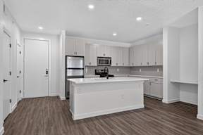 A kitchen with white cabinets and a wooden floor.