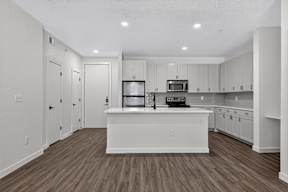 A kitchen with white cabinets and a wooden floor.