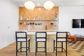 Two bar stools are in front of a bar with a wooden backsplash.