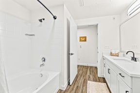 A white bathroom with a tub, sink, and mirror.
