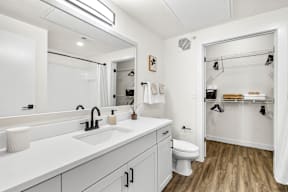 A white bathroom with a toilet, sink, and mirror.