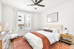 A bedroom with a bed, a chair, and a ceiling fan.