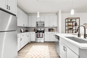A modern kitchen with white cabinets and a checkered rug on the floor.