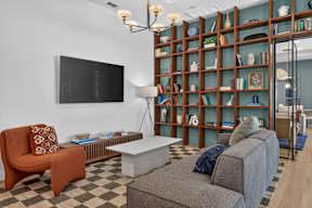 A living room with a grey couch, a brown chair, and a television on the wall.