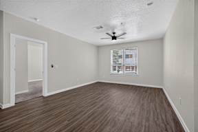 A room with a ceiling fan and a window with blinds.