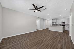 A spacious kitchen with white cabinets and a ceiling fan.