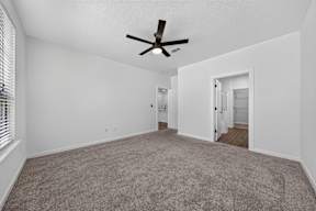A room with a ceiling fan and carpeted floor.