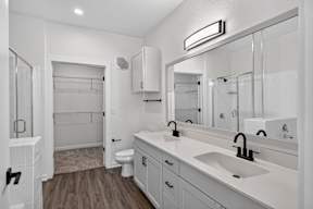 A white bathroom with a toilet, sink, and mirror.