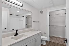 A white bathroom with a sink, toilet, and shower.