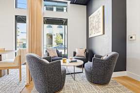 Three grey chairs are arranged around a small table in a room with a large window.