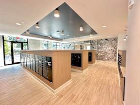 A modern kitchen with wooden floors and a large island with black appliances.