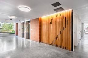 A long hallway with a wooden wall and a glass door.