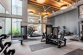 A gym with a variety of equipment including treadmills, weights, and exercise machines.