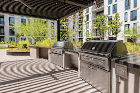 A row of outdoor grills are lined up on a patio.