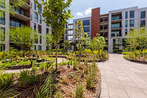 A modern building complex with a landscaped garden in front.