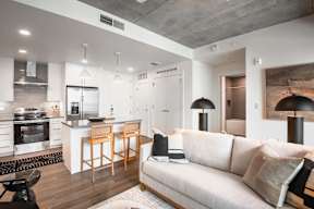 A modern living room with a kitchen area in the background.