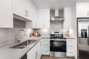 A modern kitchen with white cabinets and stainless steel appliances.