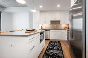 A modern kitchen with white cabinets and stainless steel appliances.