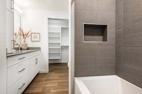 A modern bathroom with a white tub and wooden floors.
