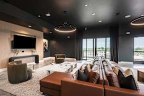 A modern living room with a long brown couch and a flat screen TV mounted on the wall.