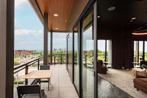 A modern balcony with a table and chairs overlooking a cityscape.