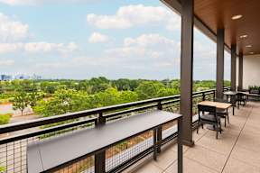 A balcony with a table and chairs overlooking a green landscape.