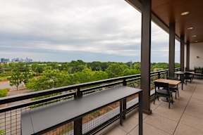 A balcony with a table and chairs overlooking a green landscape.
