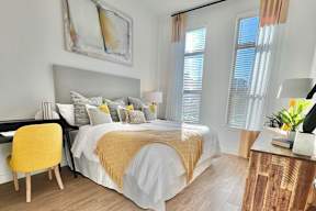 A bedroom with a large bed and a yellow chair.