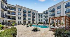 A large, modern apartment complex with a pool in the courtyard.