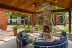 a covered patio with a fireplace and seating