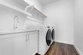 a white washer and dryer in a white laundry room with white cabinets and
