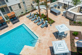 an aerial view of a swimming pool and patio with lounge chairs