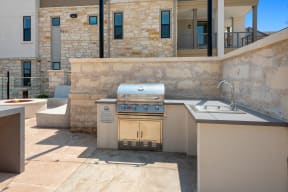 an outdoor kitchen with a grill and a sink in a backyard