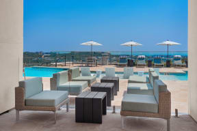 a poolside seating area with blue chairs and umbrellas at a resort
