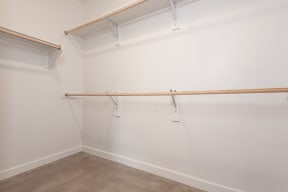 an empty room with white walls and a white walled closet and a wooden rail