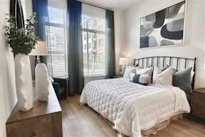 A bedroom with a large bed, a nightstand, and a painting on the wall.