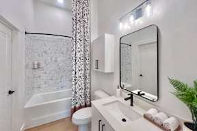 A white bathroom with a marble patterned shower.
