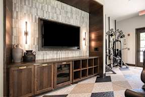 A modern living room with a flat screen TV mounted on the wall above a wooden cabinet.