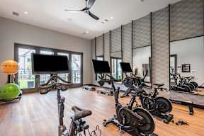 A spacious room with a variety of exercise equipment including stationary bikes and a treadmill.