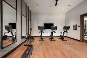 A gym with treadmills, exercise bikes, and mirrors.