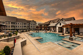 A large outdoor swimming pool surrounded by a stone wall and a walkway.